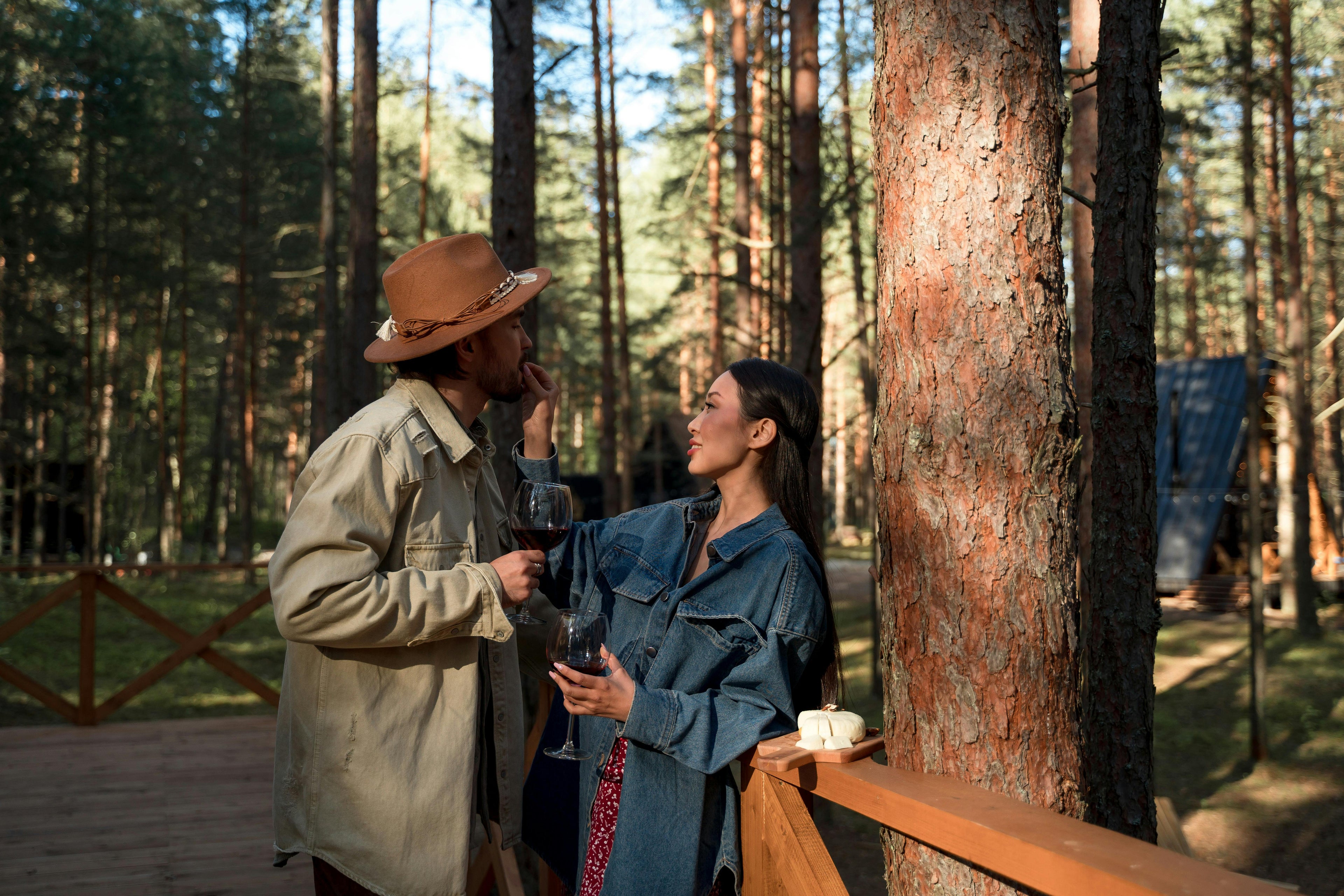 Two people standing in a forested area, both holding a glass of solo cru wine emotions red wine
