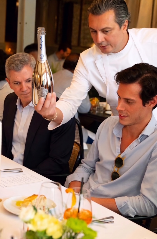 Man holding a bottle of Lamborghini at a tasting dinner with other guests.