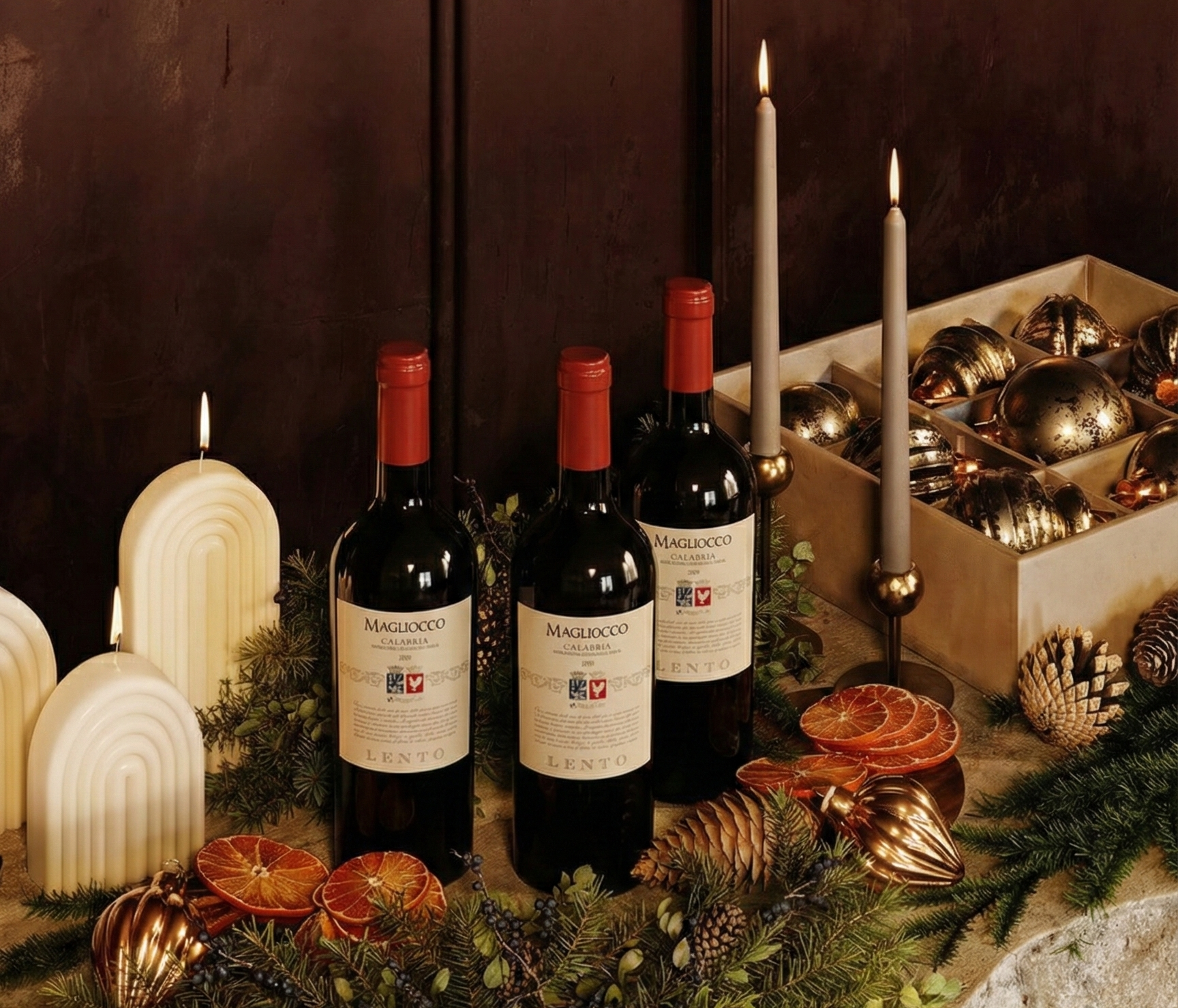 Three bottles of wine on a decorative table with candles and ornaments.